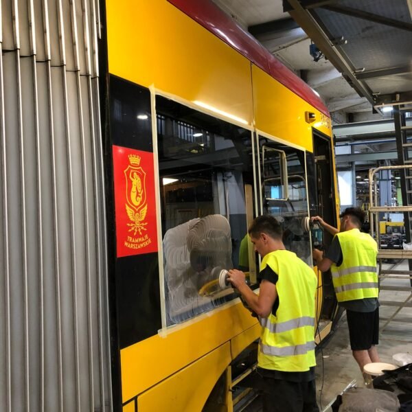 Zwei Techniker entfernen fachgerecht Kratzer von der Verglasung eines Fahrzeugs des öffentlichen Nahverkehrs